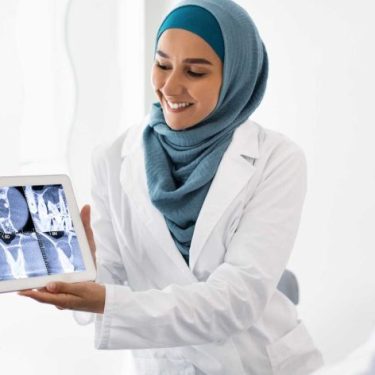 muslim-female-dentist-holding-digital-tablet-expla-ZD6MS5L-qrwc2ss15zmnutp8ub2otvea5vfetxt8ycxrowjdmg